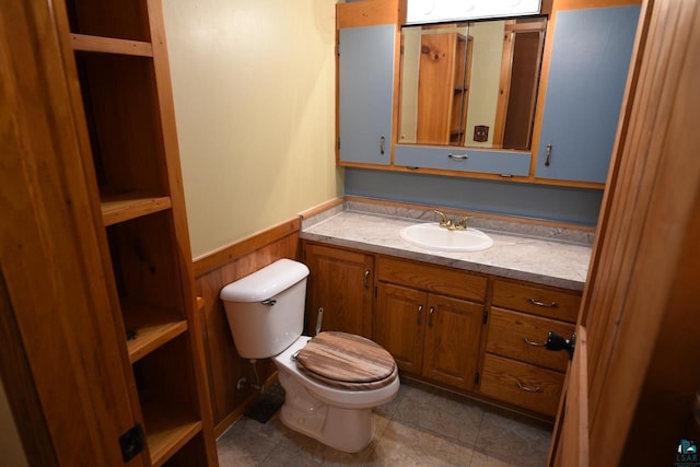 bathroom featuring vanity, wooden walls, toilet, and tile patterned floors