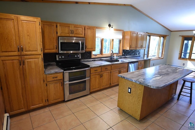 kitchen featuring a breakfast bar, a center island, sink, vaulted ceiling, and stainless steel appliances