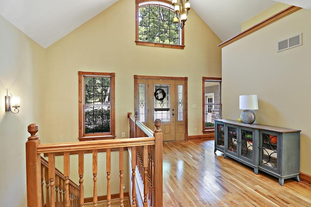 entrance foyer featuring an inviting chandelier, wood-type flooring, and high vaulted ceiling