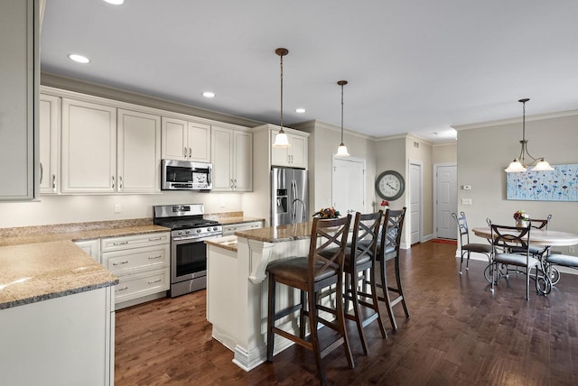 kitchen with pendant lighting, appliances with stainless steel finishes, dark hardwood / wood-style flooring, and a kitchen island