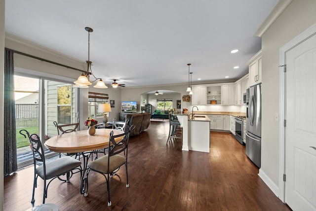 dining room with ceiling fan with notable chandelier, ornamental molding, dark hardwood / wood-style flooring, and sink