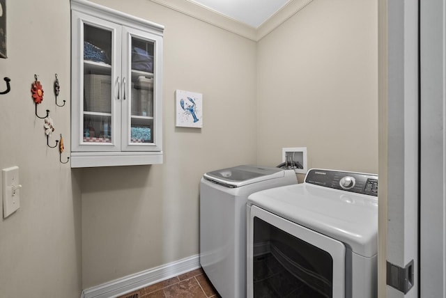 washroom with ornamental molding, washing machine and clothes dryer, and dark tile patterned floors