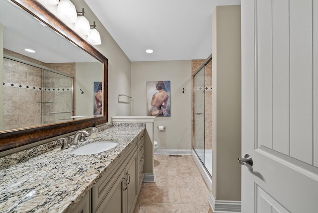 bathroom with tile patterned floors, a shower with door, vanity, and toilet