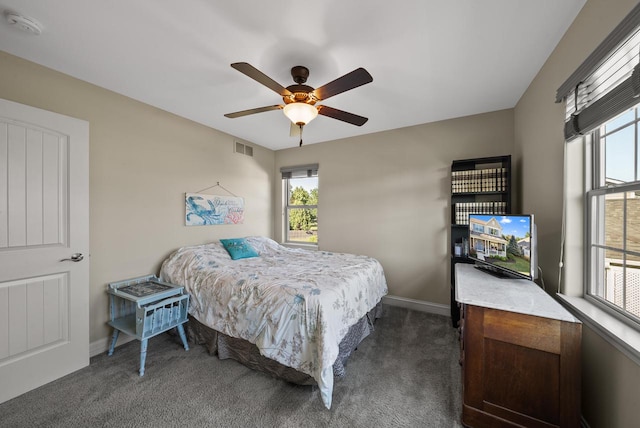 bedroom with multiple windows, dark carpet, and ceiling fan