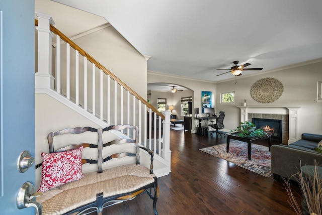 entryway with ceiling fan, a fireplace, crown molding, and dark wood-type flooring