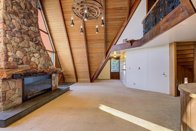 unfurnished living room with a stone fireplace, carpet flooring, beamed ceiling, and wooden ceiling