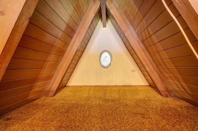 additional living space with carpet, lofted ceiling, and wooden walls