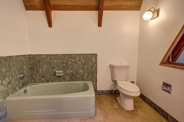 bathroom featuring beamed ceiling, toilet, and a bathing tub