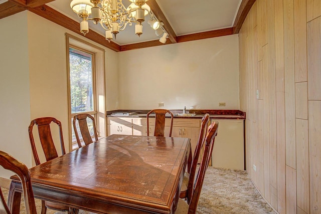 carpeted dining area with beam ceiling, a chandelier, and wooden walls