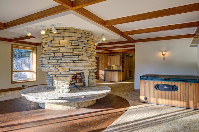 unfurnished living room with dark tile patterned flooring, rail lighting, beamed ceiling, and a fireplace