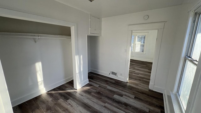 unfurnished bedroom with a closet and dark wood-type flooring