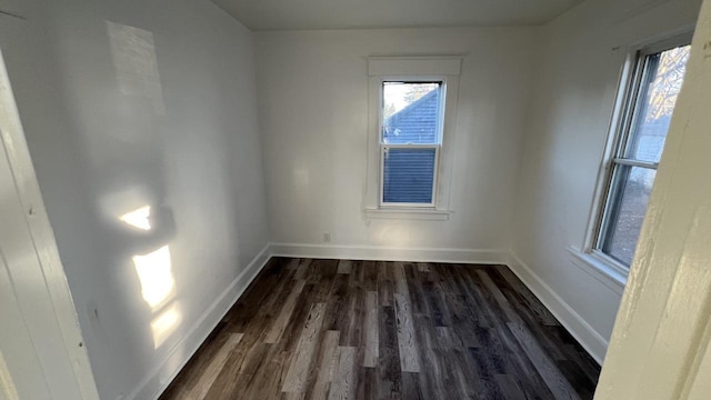 empty room with dark hardwood / wood-style flooring and a healthy amount of sunlight