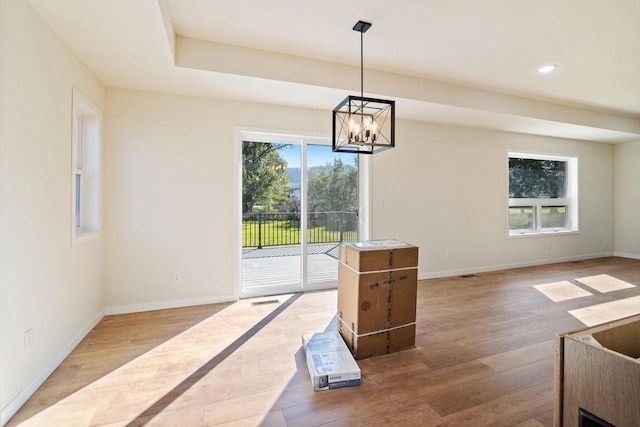 unfurnished dining area with a notable chandelier and wood-type flooring