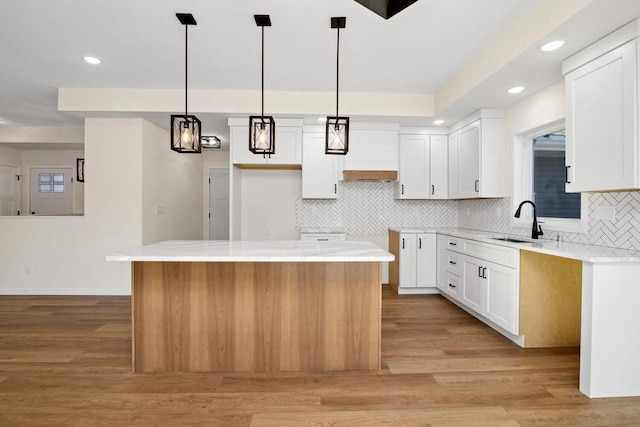 kitchen featuring white cabinets, hanging light fixtures, and a center island