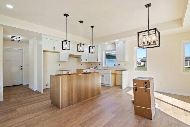 kitchen featuring pendant lighting, a chandelier, light hardwood / wood-style floors, a kitchen island, and white cabinets