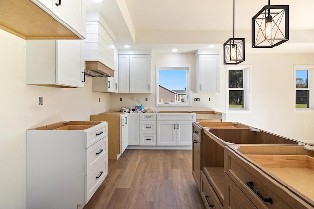 kitchen with decorative light fixtures, hardwood / wood-style flooring, and white cabinets