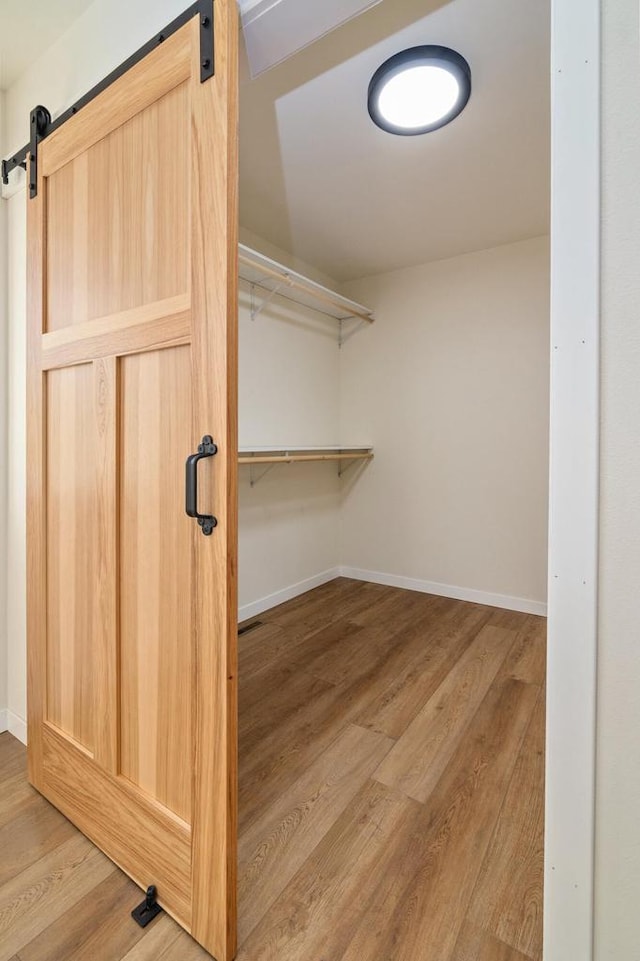 walk in closet with wood-type flooring and a barn door