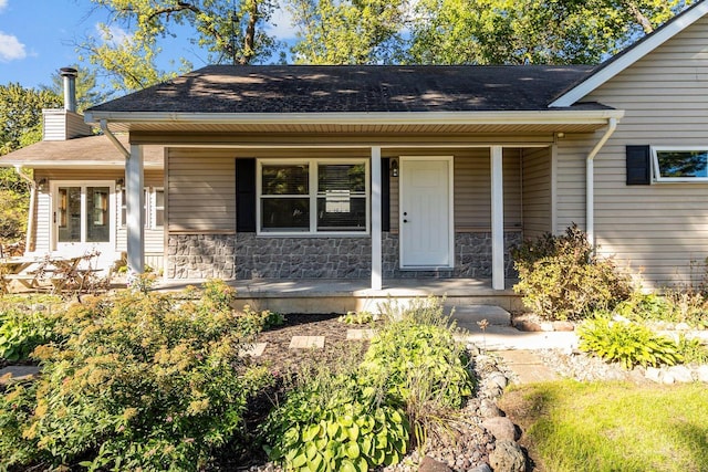W3611 S Parkway Dr, Markesan, WI 53946 - view of front of house with a porch, stone siding, a chimney, and a shingled roof