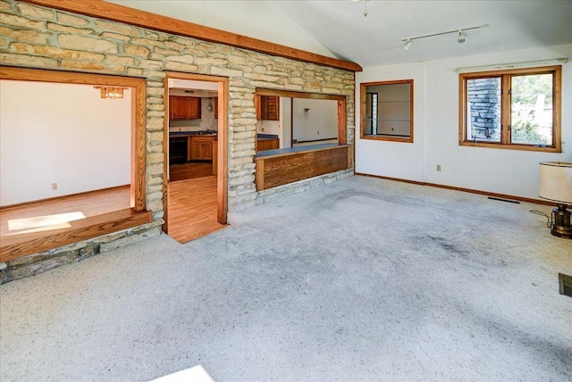 unfurnished living room with track lighting, lofted ceiling, and carpet flooring