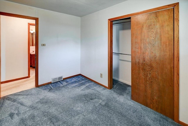 unfurnished bedroom with dark colored carpet and a closet