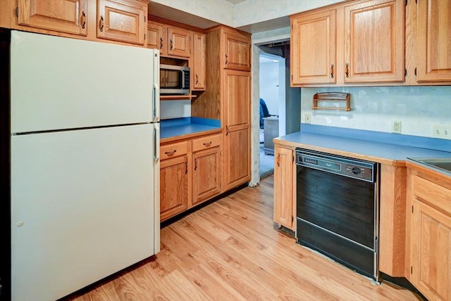 kitchen with light hardwood / wood-style flooring, black dishwasher, white fridge, and backsplash