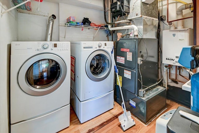 clothes washing area featuring separate washer and dryer, tankless water heater, and hardwood / wood-style floors