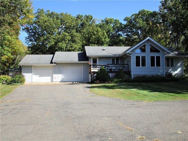 view of front of property with a wooden deck, a front lawn, and a garage