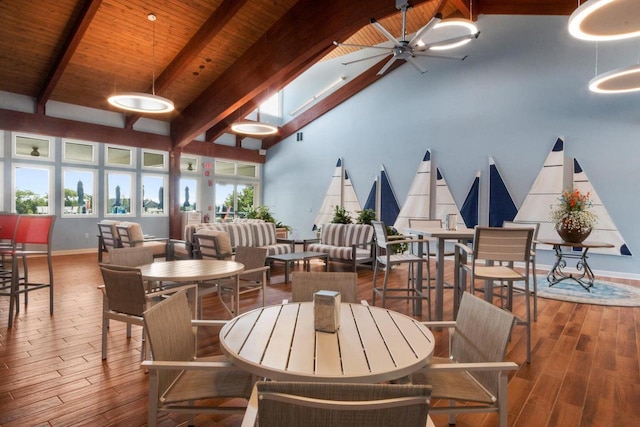 dining space featuring high vaulted ceiling, wood-type flooring, beam ceiling, and ceiling fan