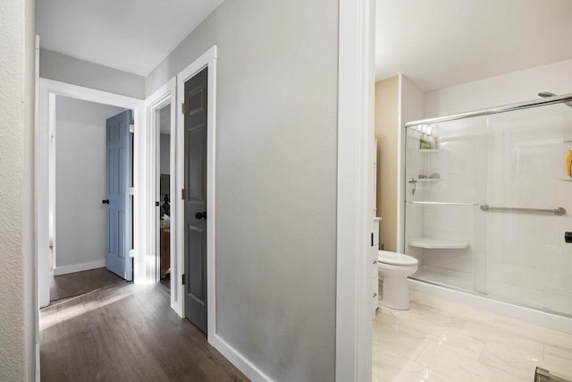 bathroom with hardwood / wood-style floors, a shower with door, and toilet