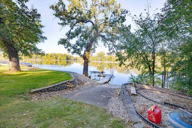 dock area with a lawn and a water view