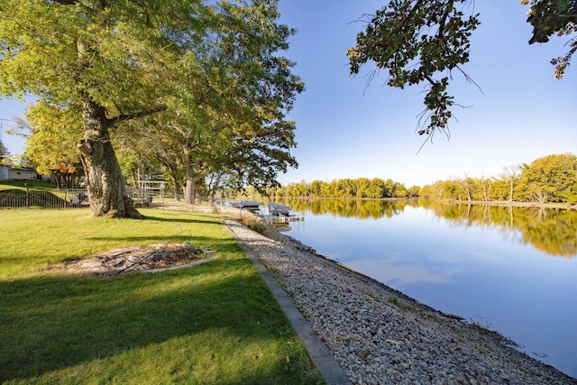 view of dock with a lawn and a water view