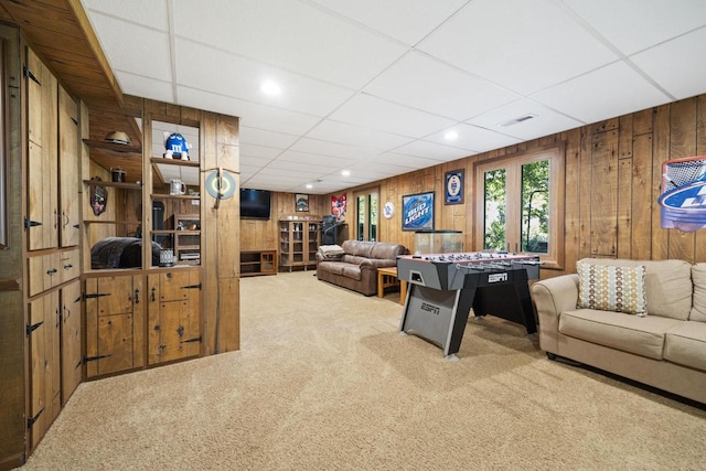 carpeted living room featuring wooden walls and a paneled ceiling