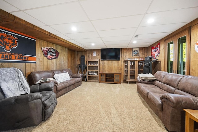 living room featuring a drop ceiling, wood walls, and carpet flooring