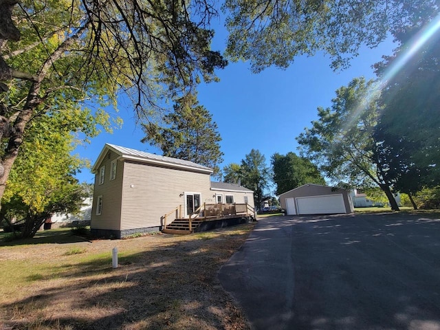 view of side of home featuring a wooden deck, a garage, and an outbuilding