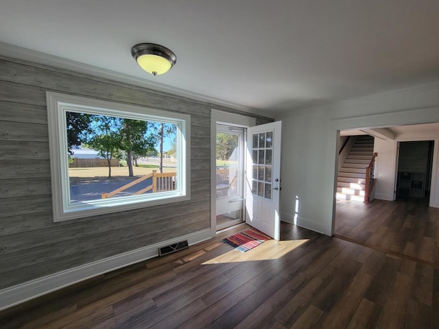 doorway to outside with ornamental molding, dark hardwood / wood-style flooring, and wooden walls