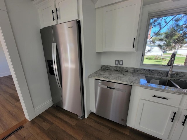 kitchen with light stone countertops, sink, stainless steel appliances, white cabinets, and dark wood-type flooring