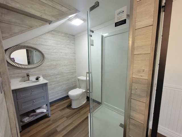 bathroom with an enclosed shower, hardwood / wood-style floors, toilet, wooden walls, and vanity