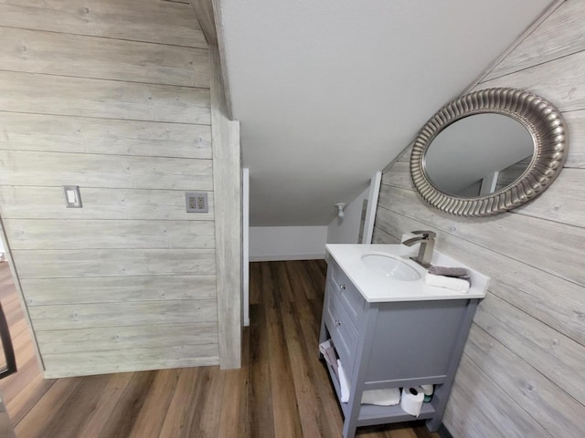 bathroom featuring vanity, vaulted ceiling, wood-type flooring, and wood walls