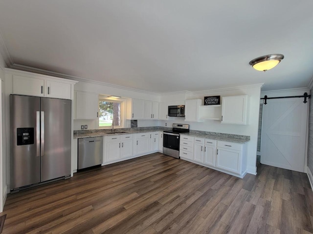 kitchen featuring appliances with stainless steel finishes, white cabinetry, a barn door, and dark hardwood / wood-style flooring