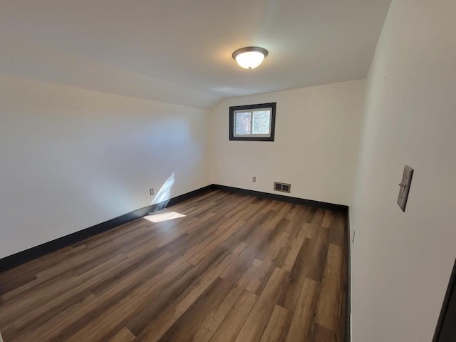 spare room featuring lofted ceiling and dark wood-type flooring