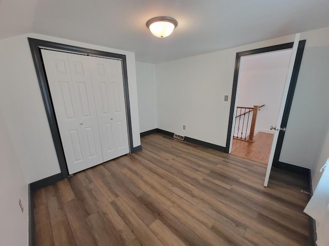 unfurnished bedroom with a closet and dark wood-type flooring