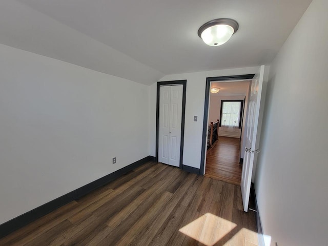 unfurnished bedroom with a closet, vaulted ceiling, and dark hardwood / wood-style flooring