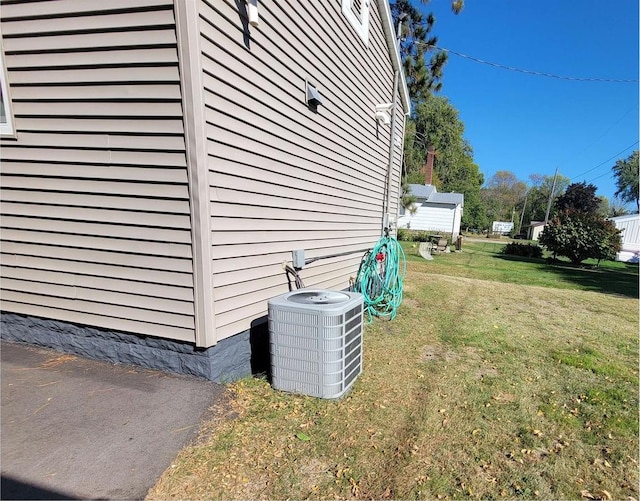 view of side of property featuring central air condition unit and a yard