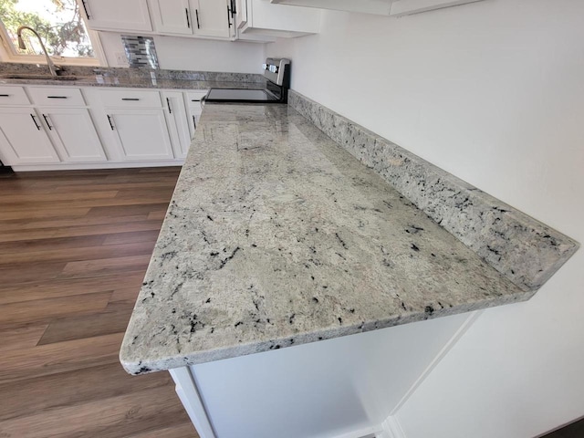 interior details with white cabinetry, kitchen peninsula, sink, and stainless steel range