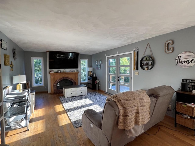 living room featuring wood-type flooring, a fireplace, french doors, and a wealth of natural light