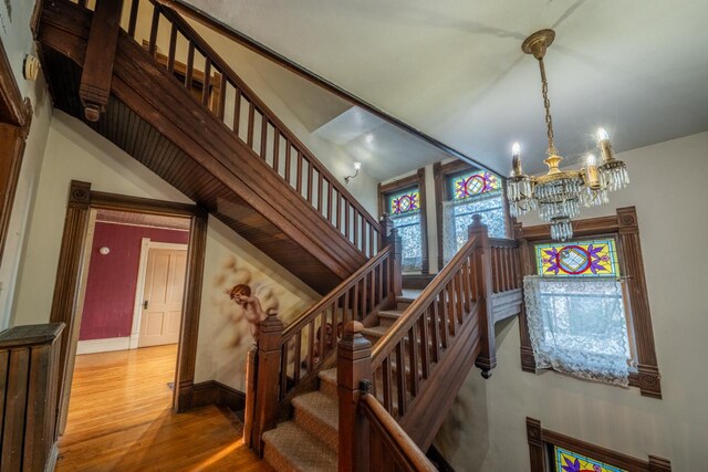 stairs with a notable chandelier and wood-type flooring