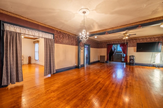 unfurnished living room featuring crown molding, hardwood / wood-style flooring, and ceiling fan with notable chandelier