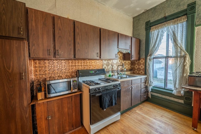 kitchen featuring sink, light hardwood / wood-style floors, and white gas stove