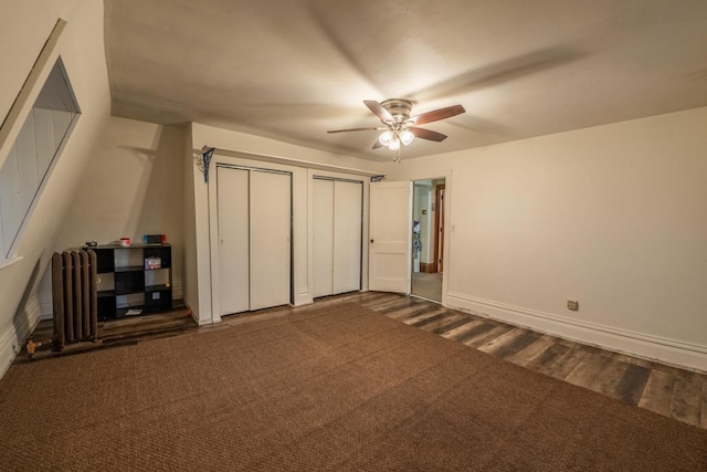 unfurnished bedroom with multiple closets, dark carpet, and ceiling fan