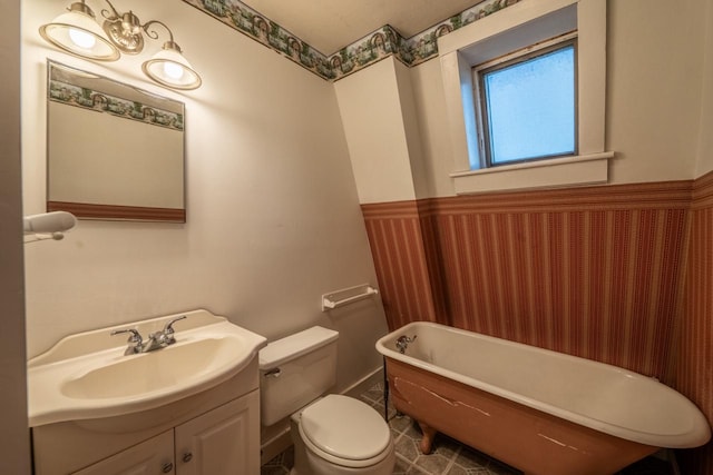 bathroom featuring vanity, a bath, and toilet